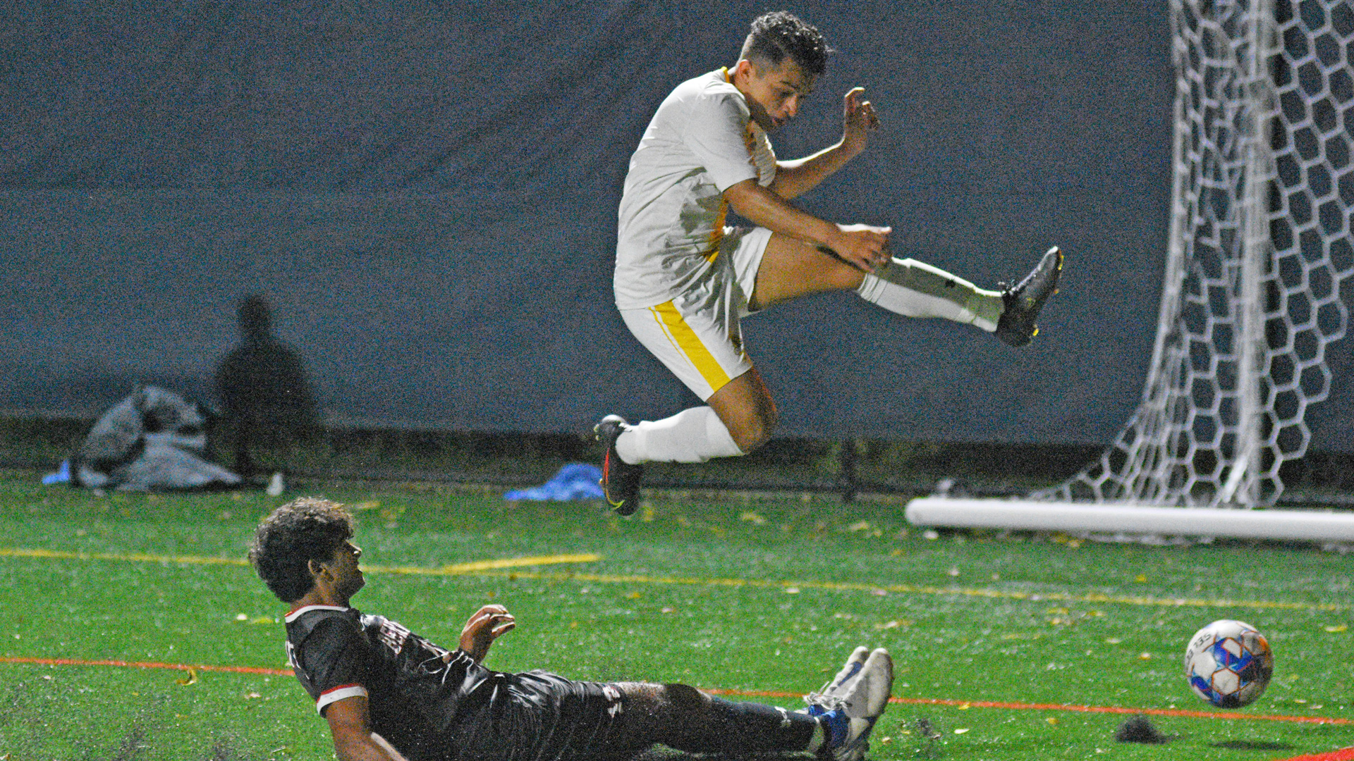 Elvin Carrasco leaping over a sliding defender